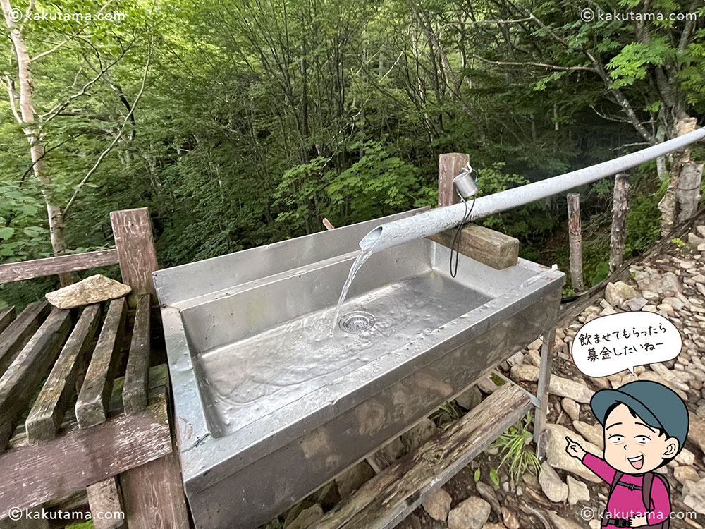 甲斐駒ヶ岳へ向かう登山道沿いに建つ仙水小屋の水場の写真と登山者のイラスト